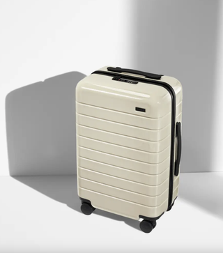 a glossy white suitcase in front of a plain backdrop