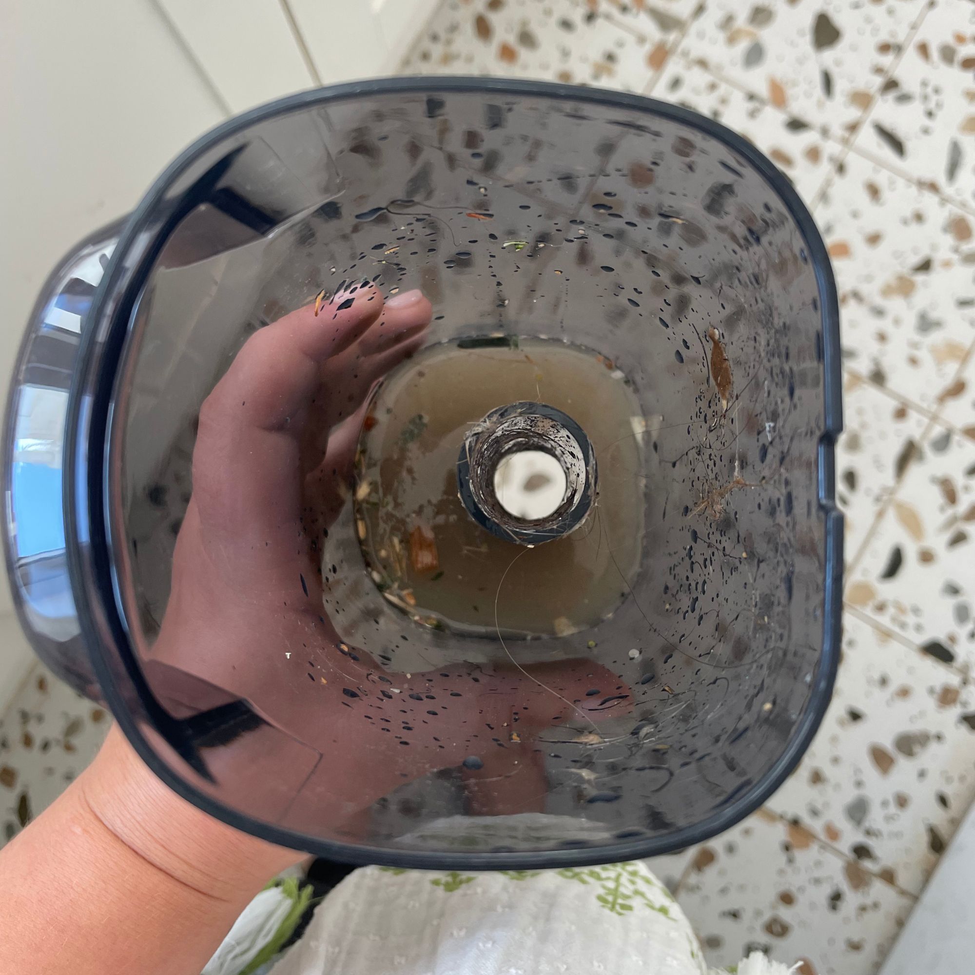 Hand holding a dirty water tank with brown water in it