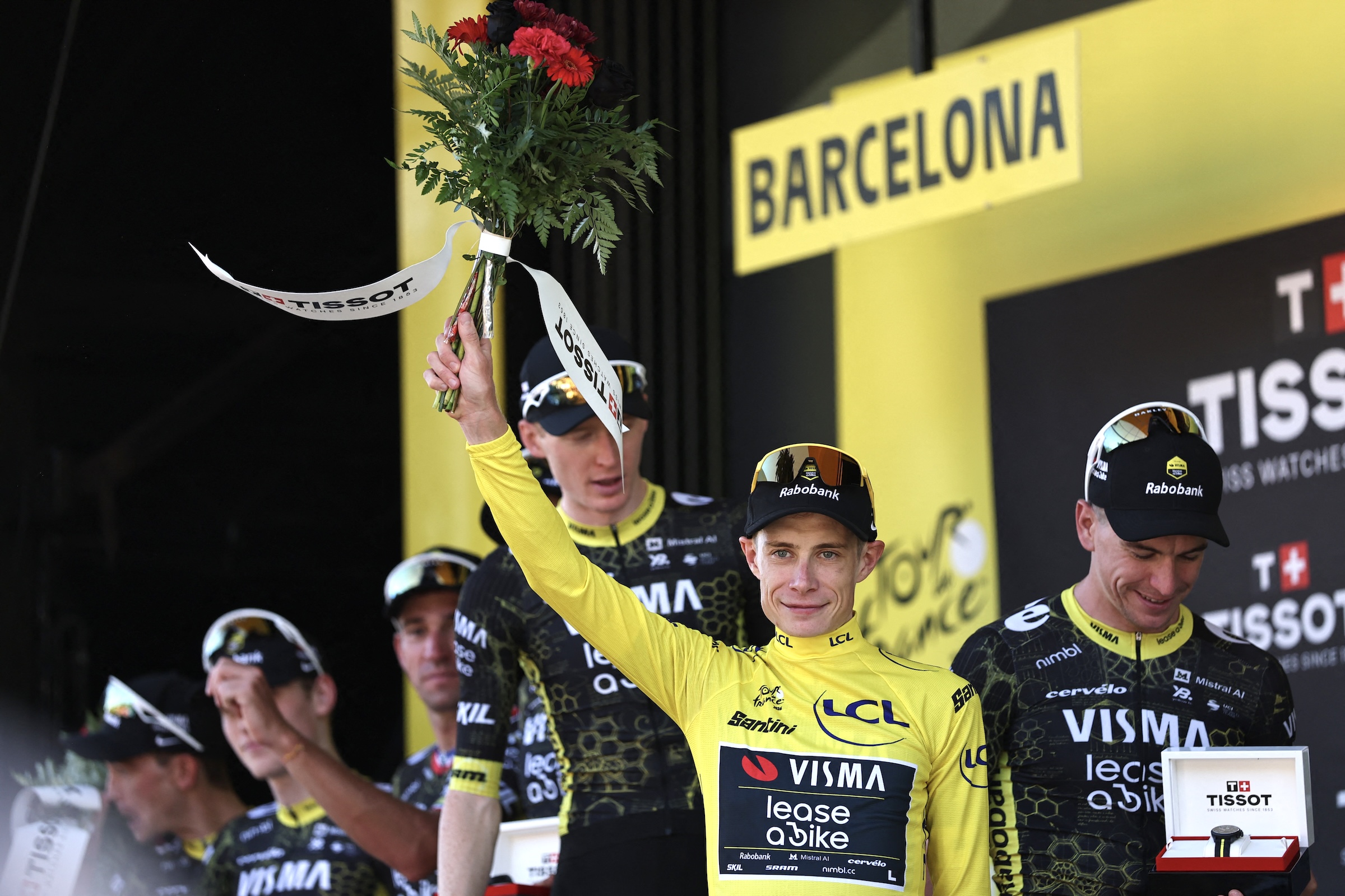 Jonas Vingegaard celebrates on the podium wearing the yellow jersey with his teammates