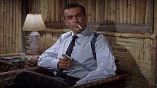 Sean Connery cooly aims his gun in his hotel room in Dr. No.