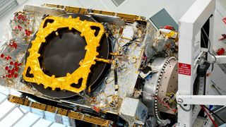 An intricate, gold-plated Eutelsat telecommunications satellite sits in a lab