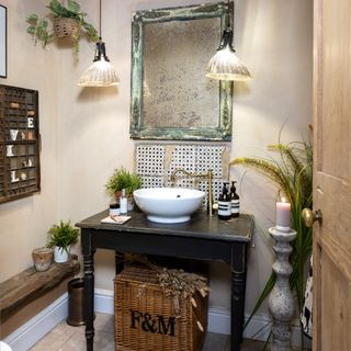 antique console table sink unit, with small tiled splashback, tall pillar candle and antiqued, foxed mirror