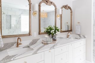 granite countertop in bathroom with twin sinks and three mirrors on wall