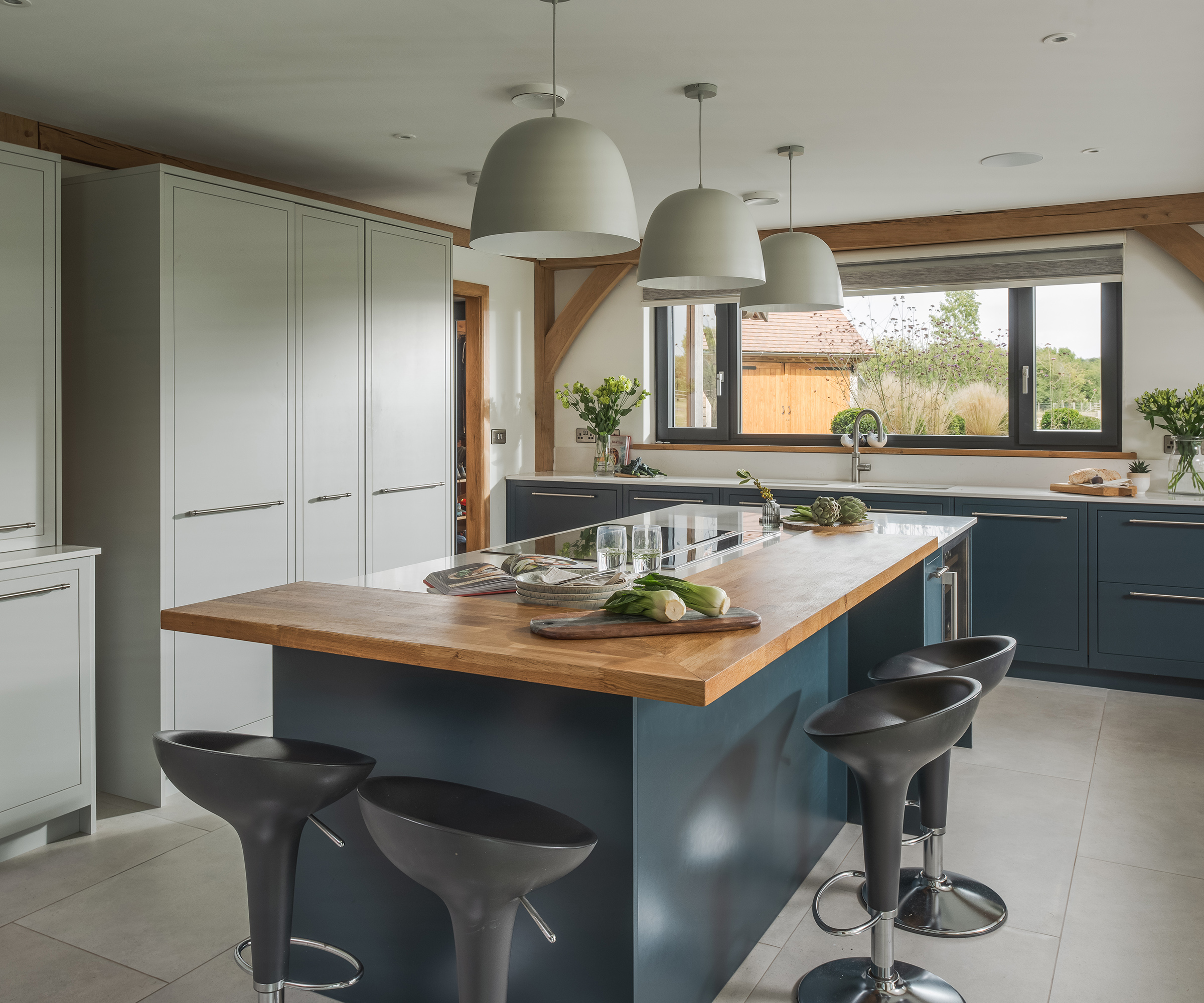 A kitchen island with timber surface and black bar stool seating