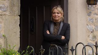 Charity Dingle smiling with her arms crossed in the doorway