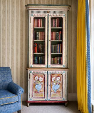 Wallpapered room with a hand painted cabinet by Decorative Artist Tess Newall and yellow curtains