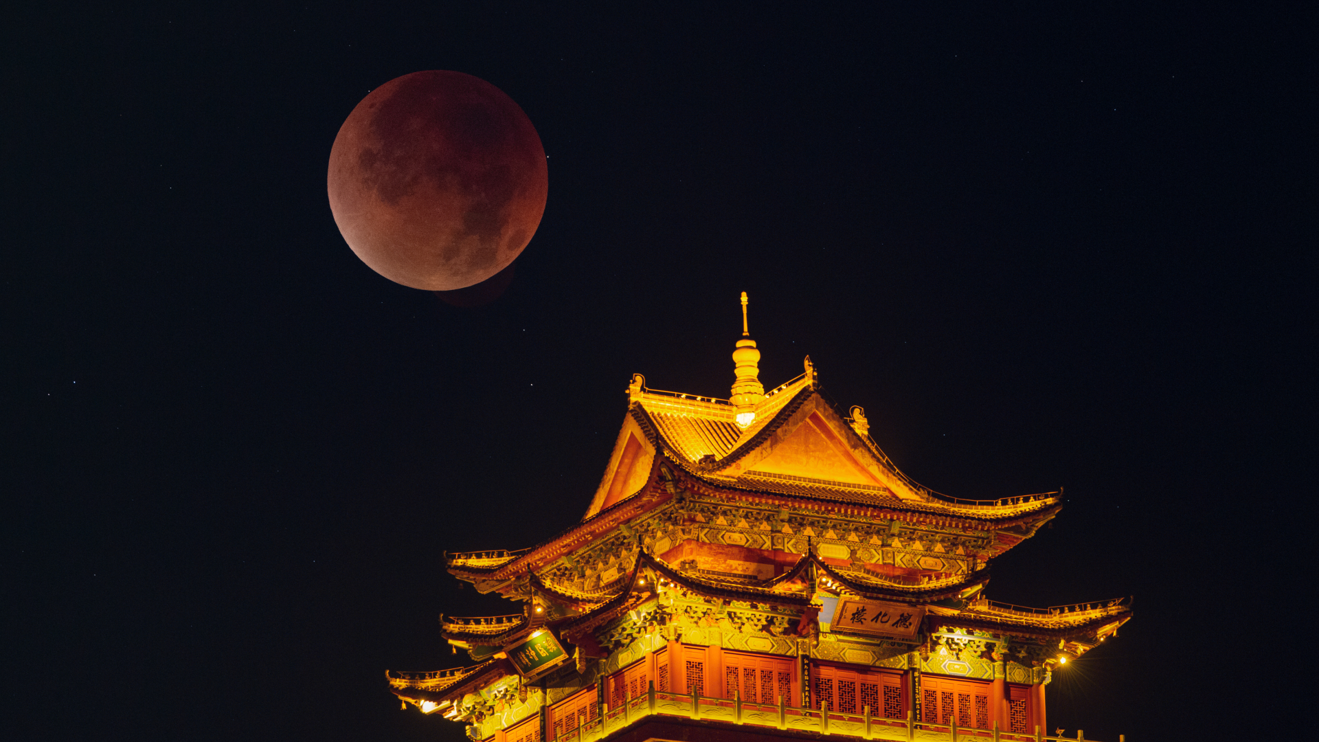 A red moon is visible in a dark sky above a yellow-lit building with a pointed roof.
