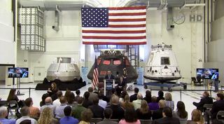 NASA Administrator Charles Bolden (center) speaks to a crowd of agency officials and dignitaries during a State of NASA speech to unveil the 2016 budget proposal at the Kennedy Space Center in Florida. NASA's Orion spacecraft (rear center), SpaceX's Drago
