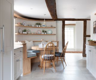 curved seating area in kitchen with built in seating, round table and wooden chairs
