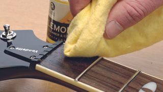 A man cleans the fretboard of a guitar