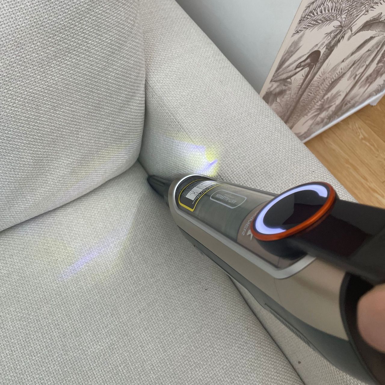 Using the handheld of the Shark PowerDetect Transformer Corded Upright Vacuum Cleaner to vacuum the side of a sofa