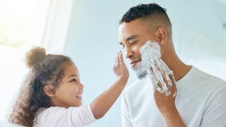 A little girl and her father are playing around with shaving cream in a bathroom at home.