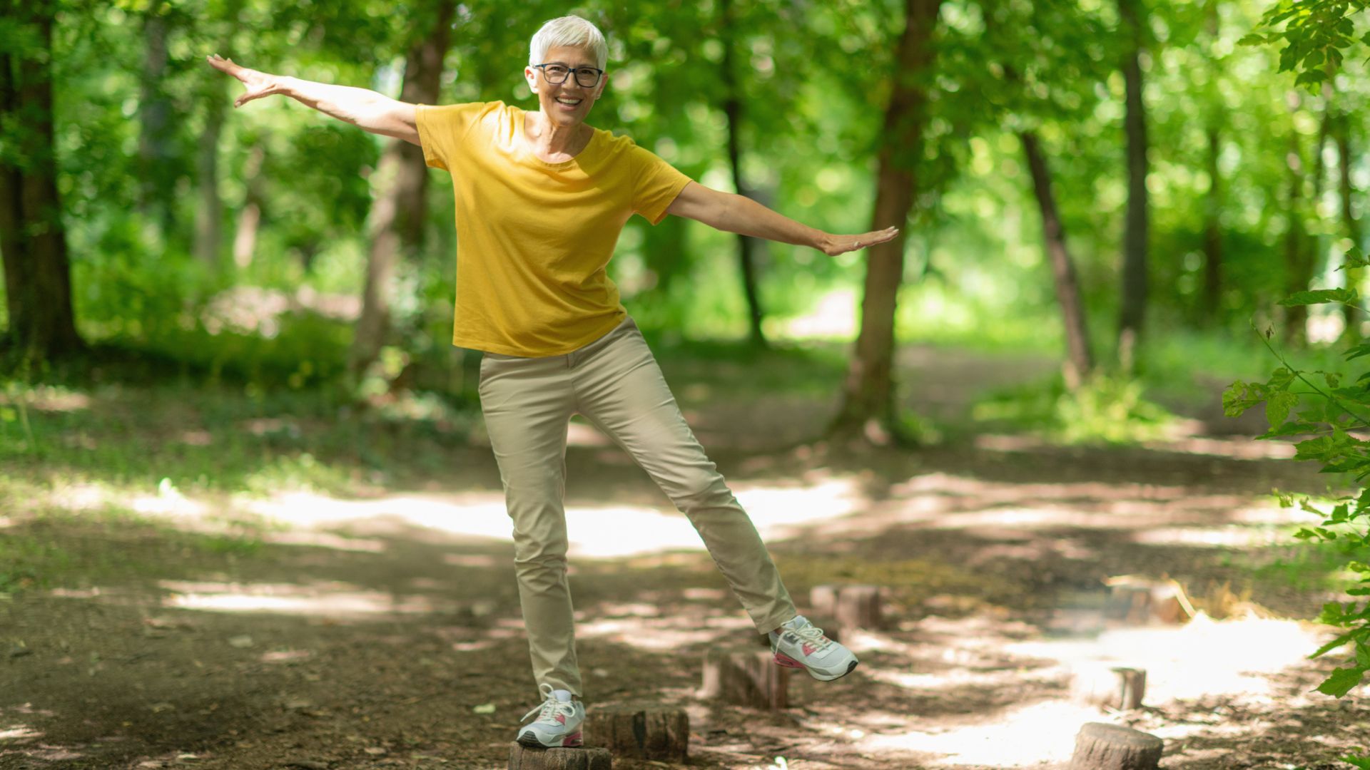 woman balances on one leg on tree stump