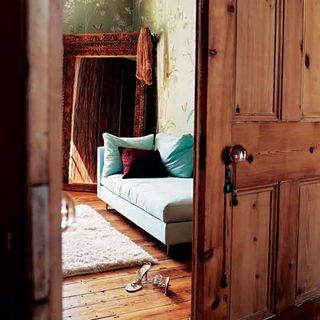 dressing room with mirror wooden door white sofa and wooden flooring