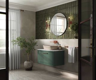 bathroom with green tiled wall, wall mounted vanity unit with countertop sink, rose gold tapes and circular mirror above