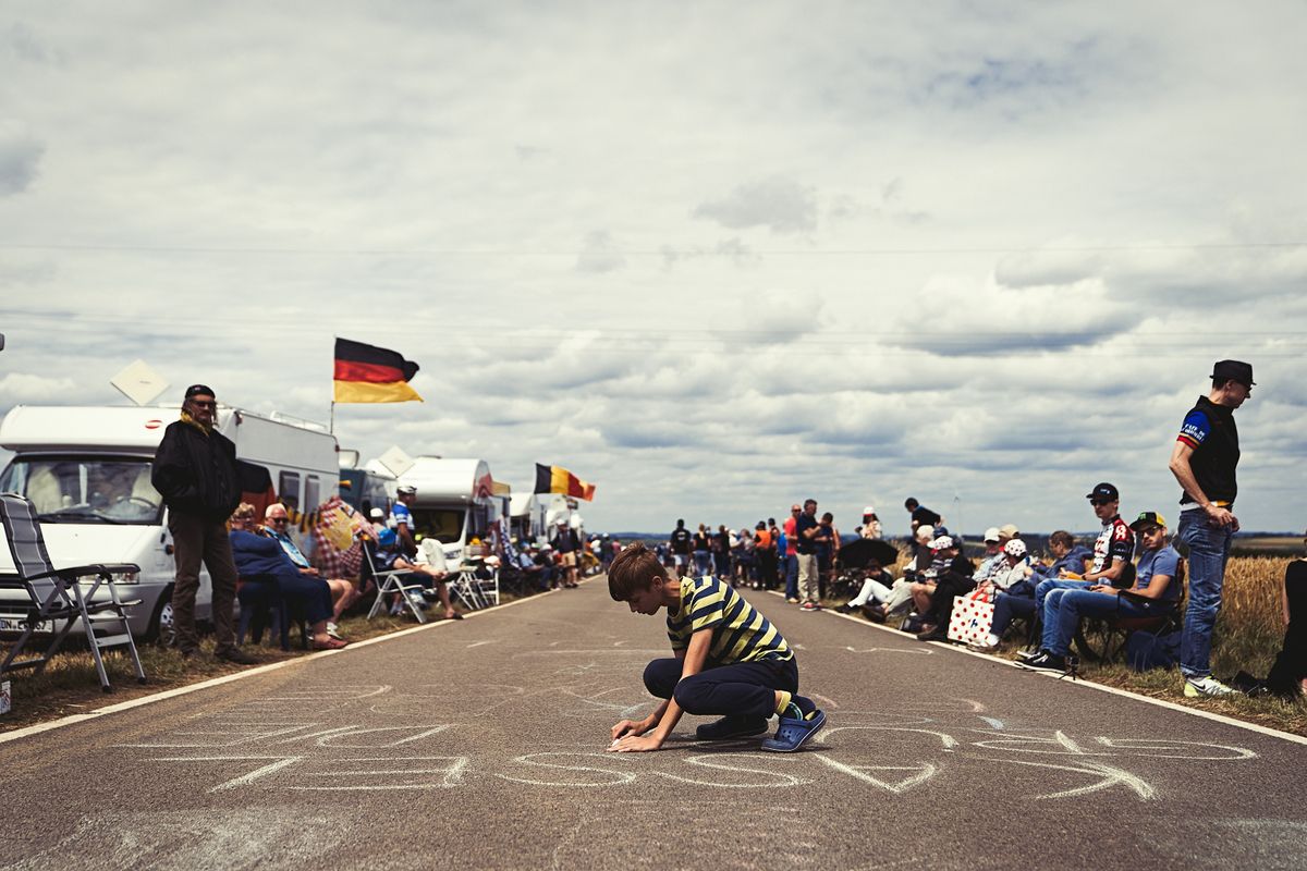 A fan applies the finishing touches to his chalk work