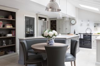 A large white kitchen with skylights and gray banquette seating.