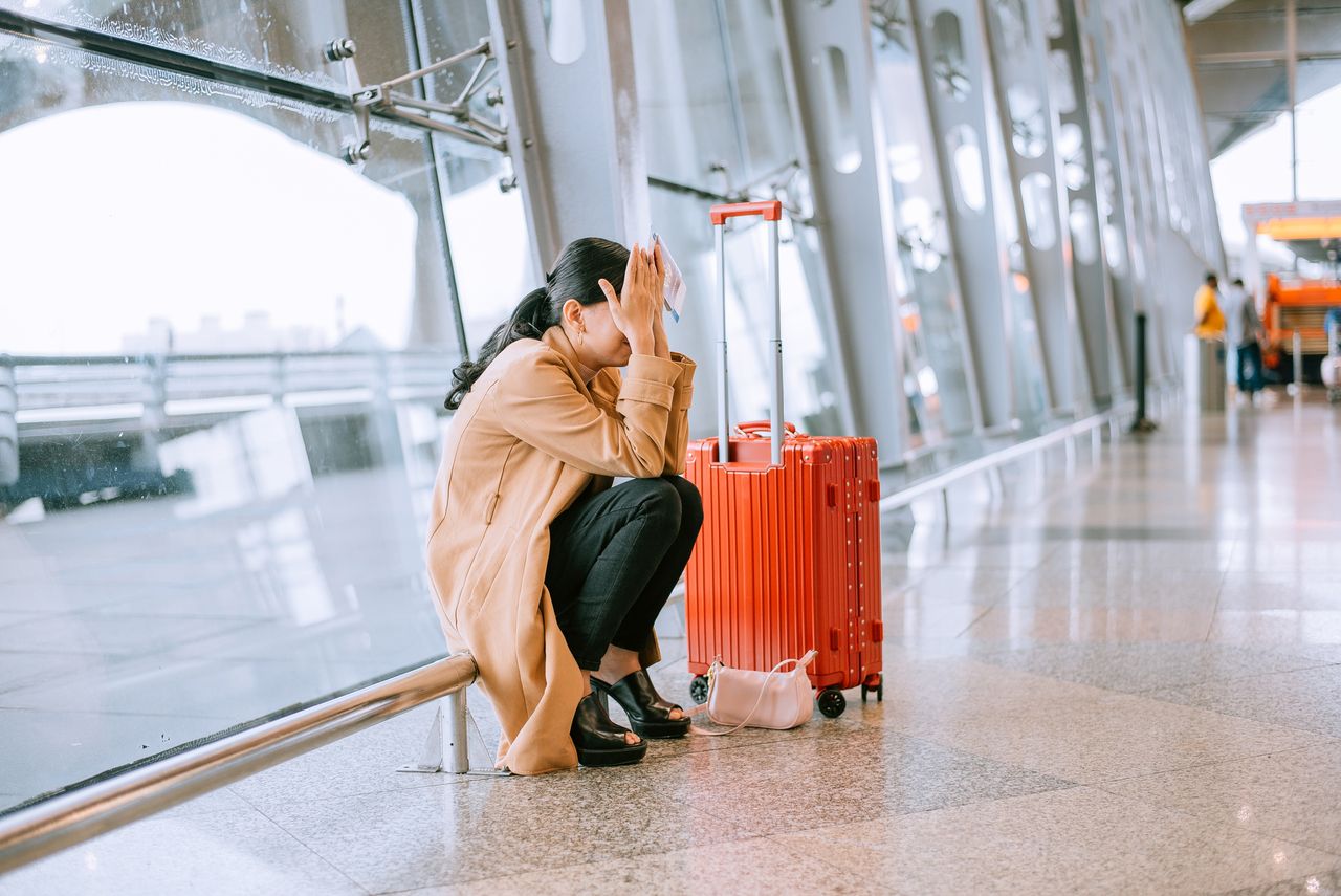 woman sitting in airport after flight cancelled