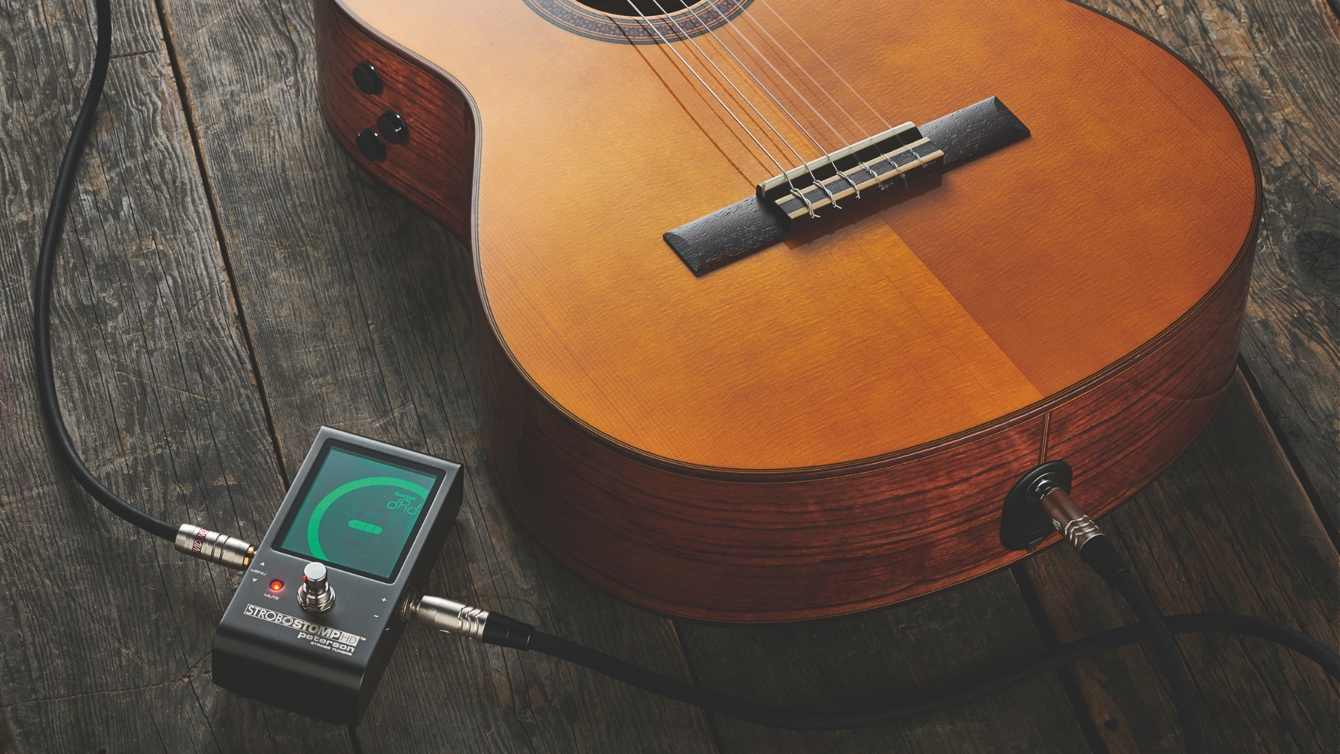 A Peterson StroboStomp guitar tuner plugged into an acoustic guitar