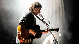 Mitch Rowland playing an acoustic guitar onstage at The Fillmore on February 25, 2024 in San Francisco, California
