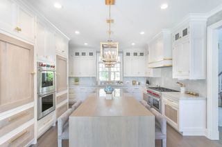white kitchen with gold chandelier and hardware and chrome appliances