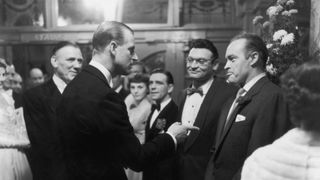 Prince Philip, Duke of Edinburgh, (left) stresses a point to US comedian Bob Hope (1903 - 2003) at a party after the Royal Variety Show at the London Palladium. Frankie Laine and Norman Wisdom look on