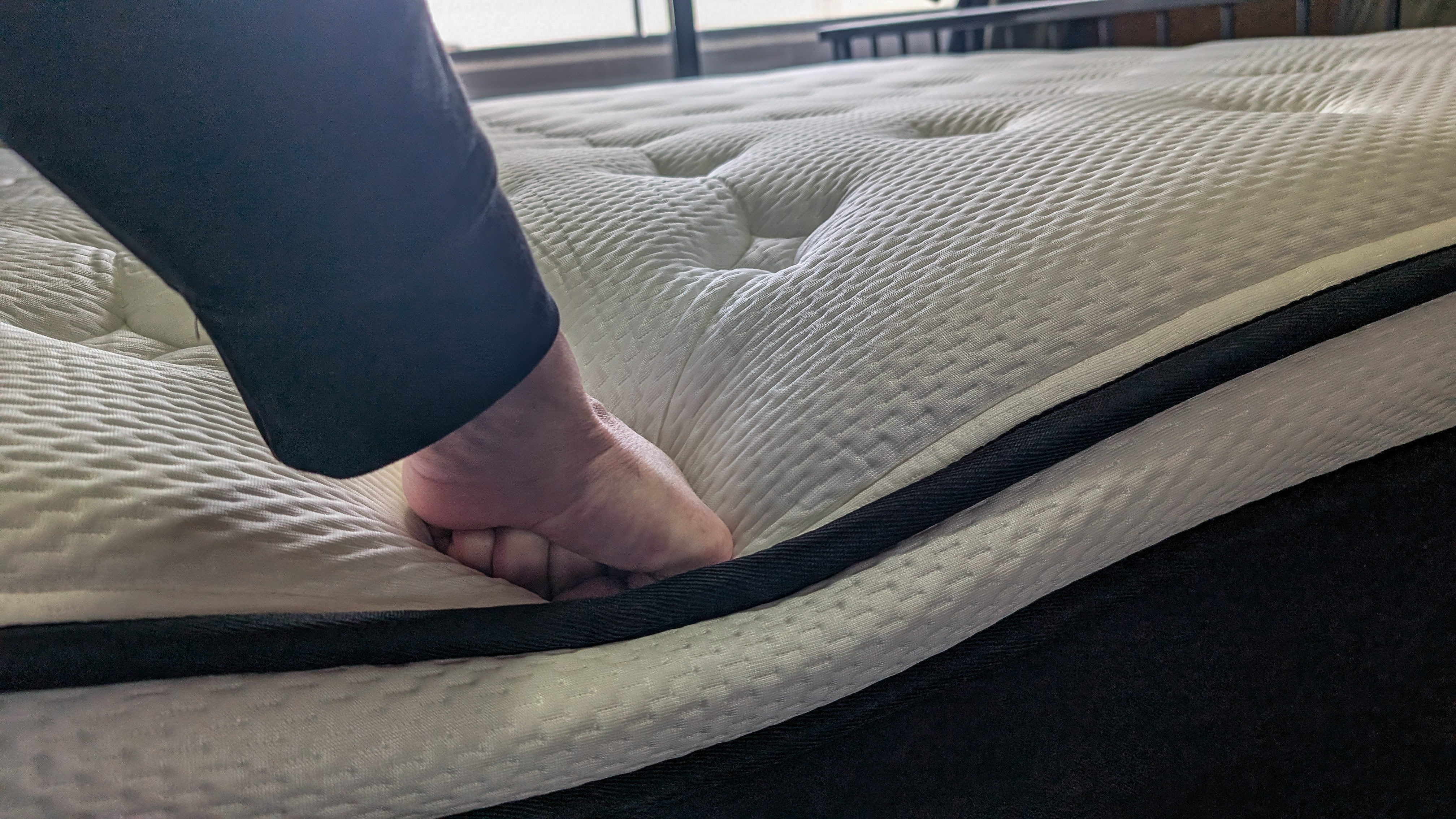 A fist pushing down on one edge of the Origin LumbarCloud mattress