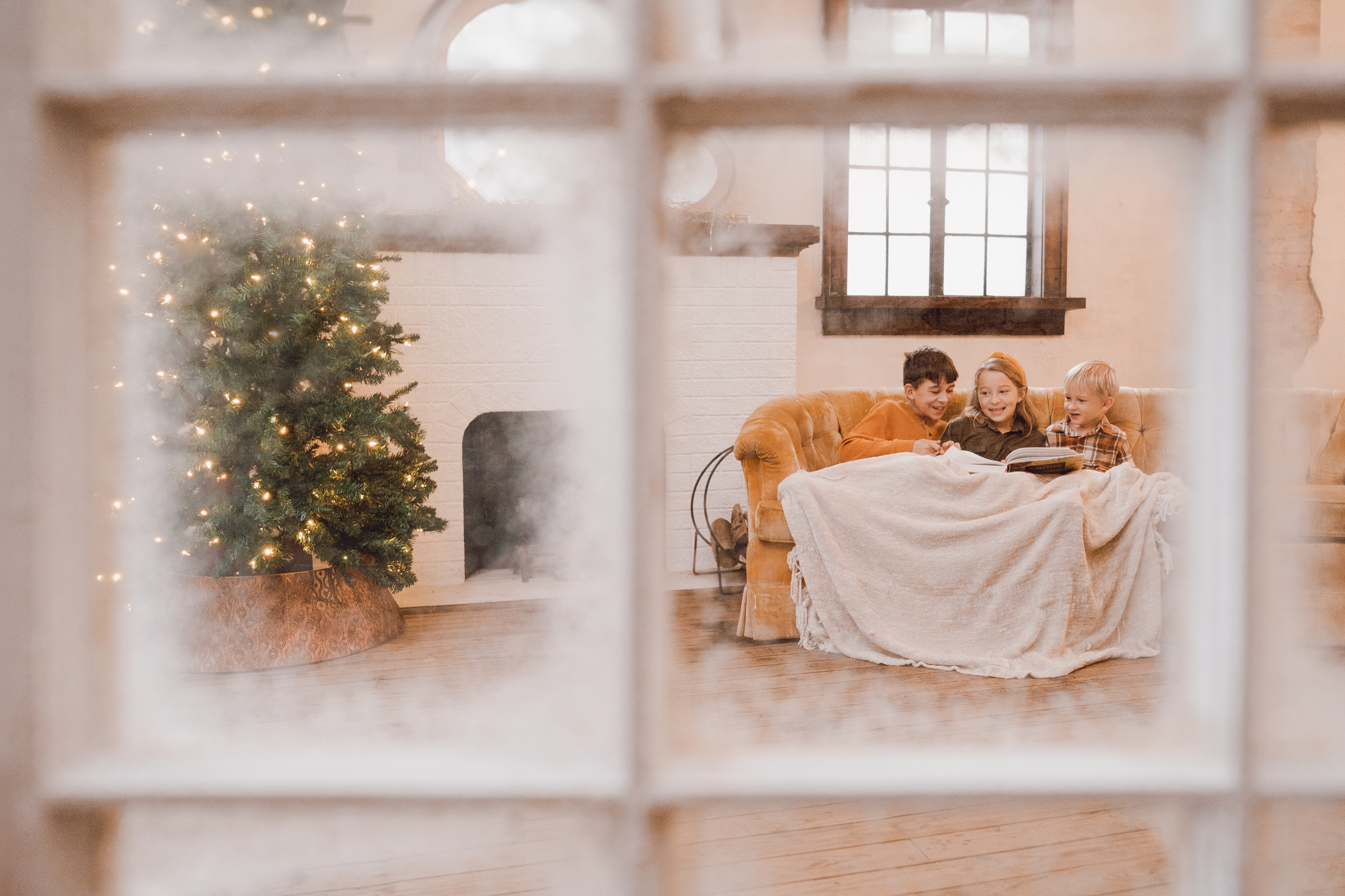 A snowy window frames a cozy Christmas scene