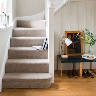 hallway with wood flooring and a carpeted stairwell
