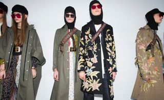 Models wear khaki coats with flower details, ivy caps, sunglasses and cross-body bags