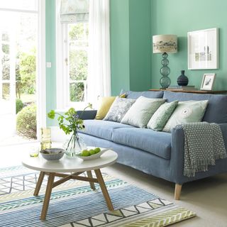 living room with sofa and cushions and pastel green walls