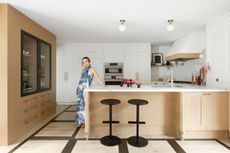 a woman in a blue dress in a modern oak kitchen