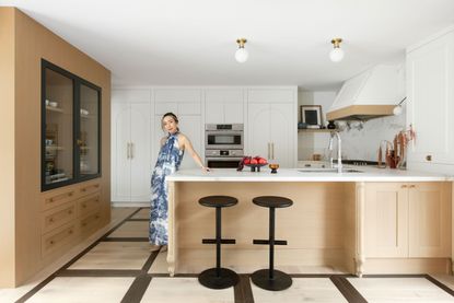 a woman in a blue dress in a modern oak kitchen