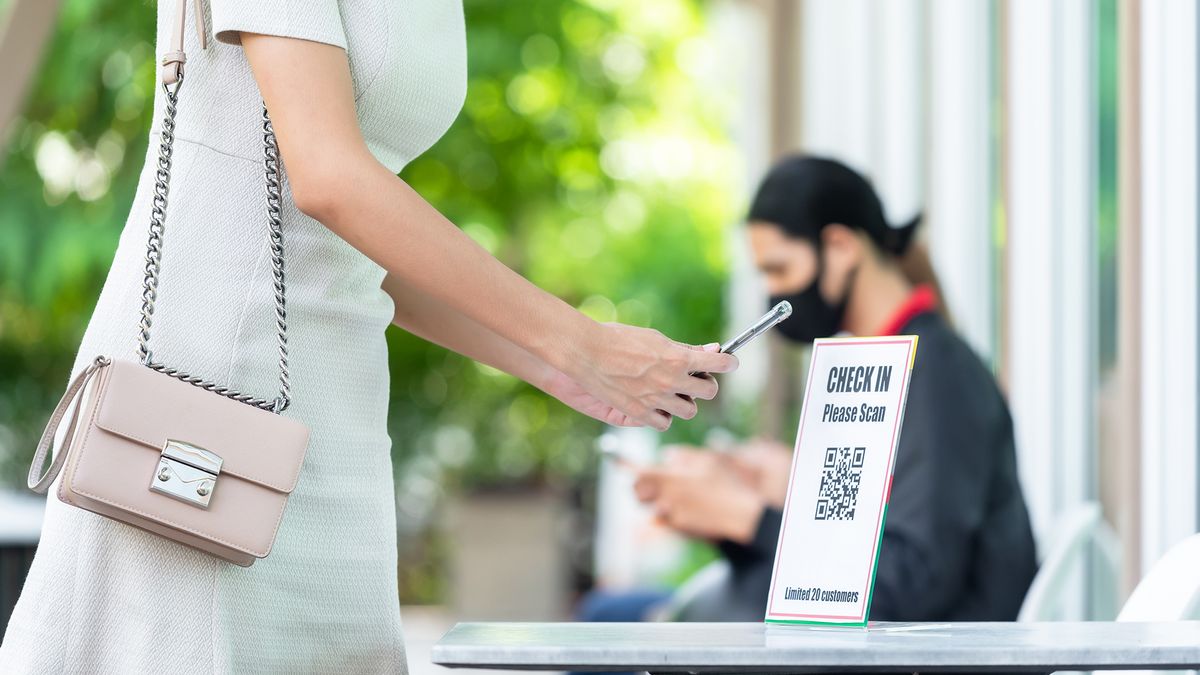 A woman scanning a QR code to demonstrate contact-tracing