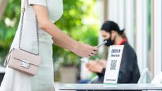A woman scanning a QR code to demonstrate contact-tracing