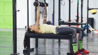 Woman doing bench press with dumbbells