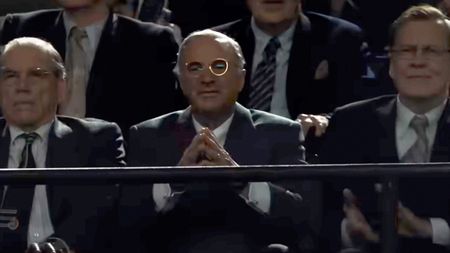 Kevin O'Leary sitting with his finger tips touching each other in Marty Supreme