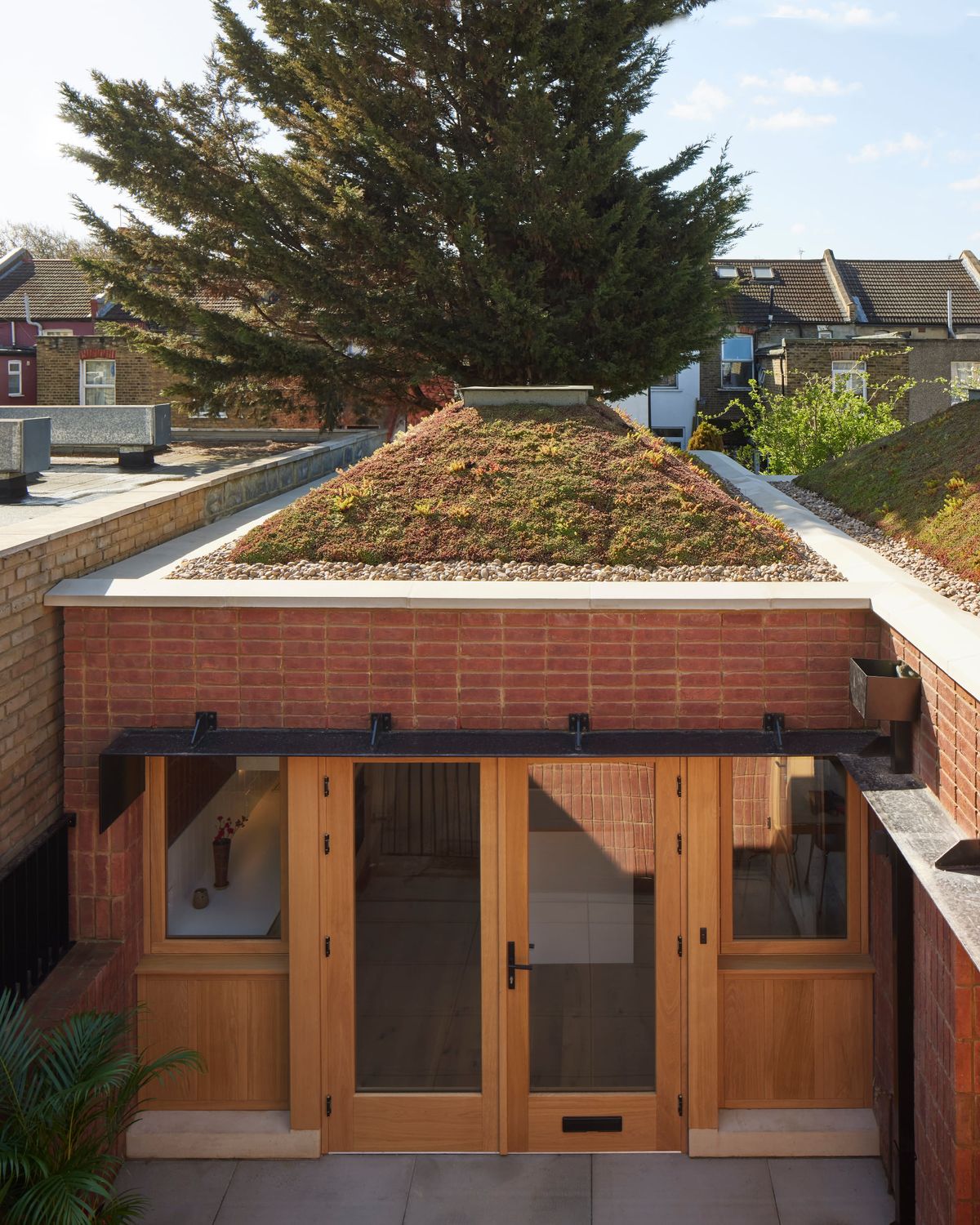 A single storey brick house with a sedum roof with a skylight
