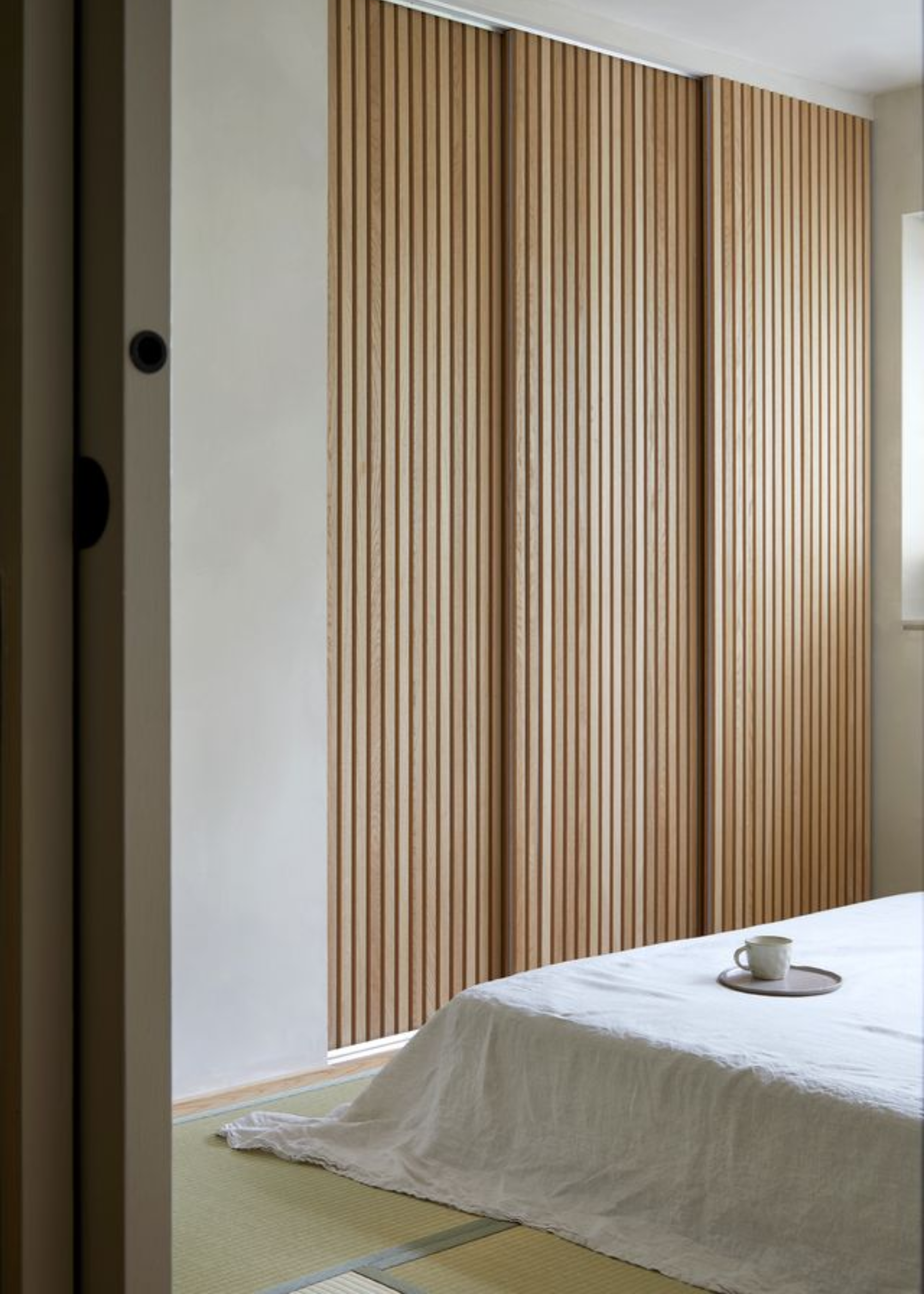 A floor mattress in a bedroom with wood panelled doors
