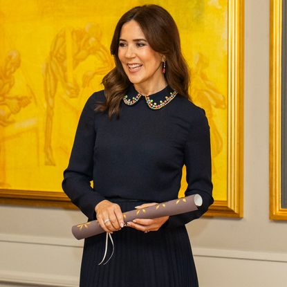  Queen Mary wearing a navy outfit and smiling