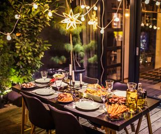 Dinner party on a deck with string lights