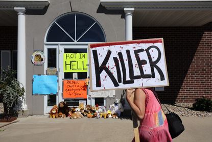 Protestor holds up sign outside dentist office of lion hunter