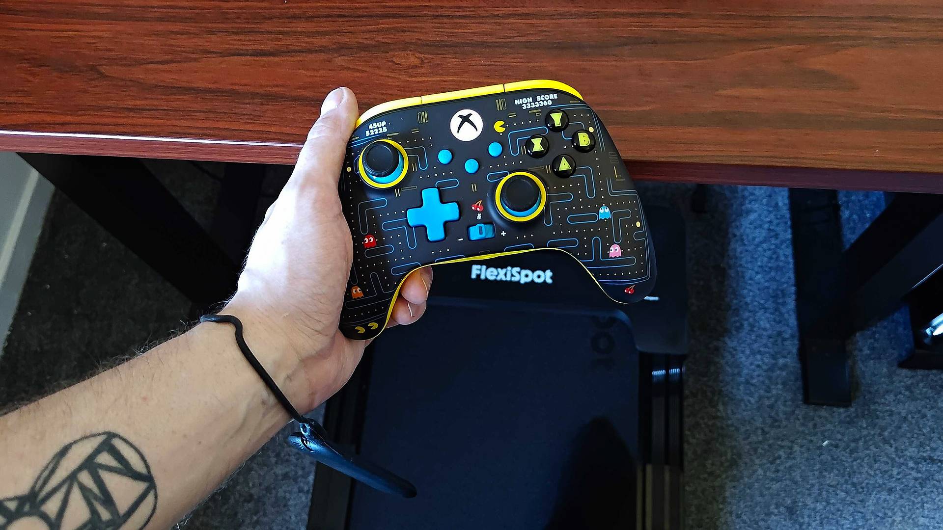 Phil Hayton holding Pac-Man PowerA controller with Flexispot Treadmill remote around wrist.