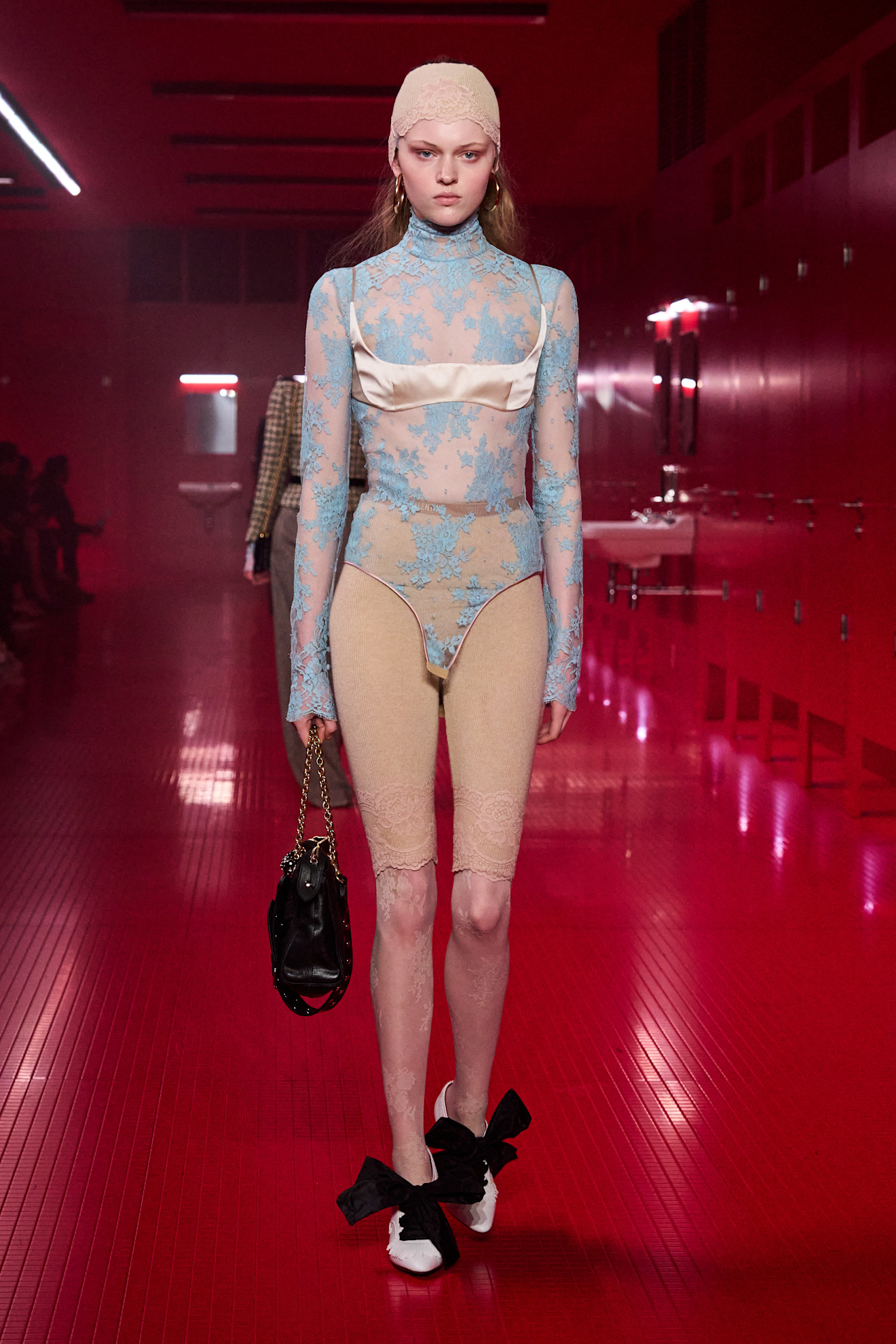 Uma modelo que andava no show F/W 25 Valentino durante a Paris Fashion Week, vestindo uma roupa de renda com empurradores de pedal de renda e uma bralette de cetim.