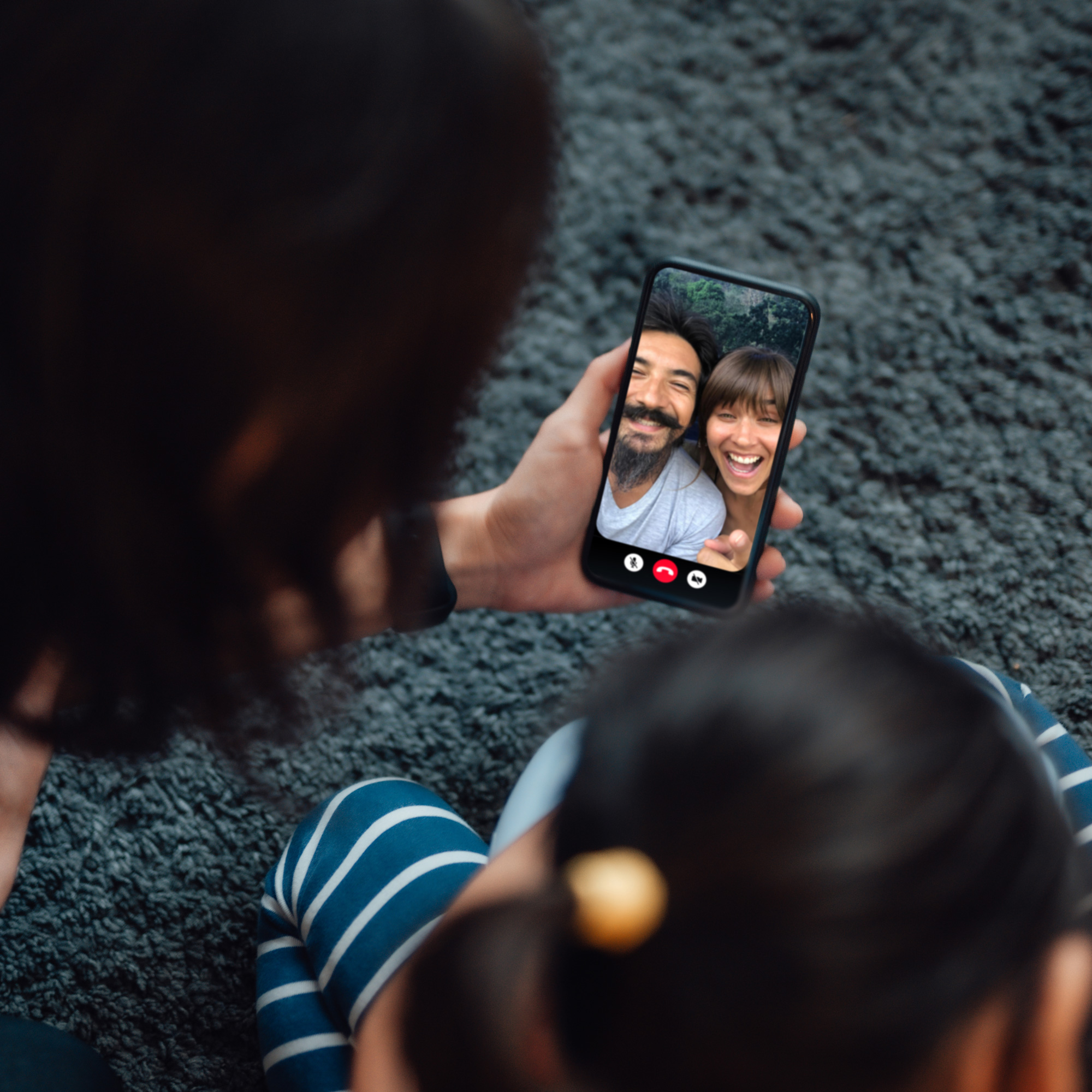 close up of a family on a smartphone video call with another couple