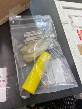 a plastic bag with several pennies and a yellow cylinder inside it rests on a table