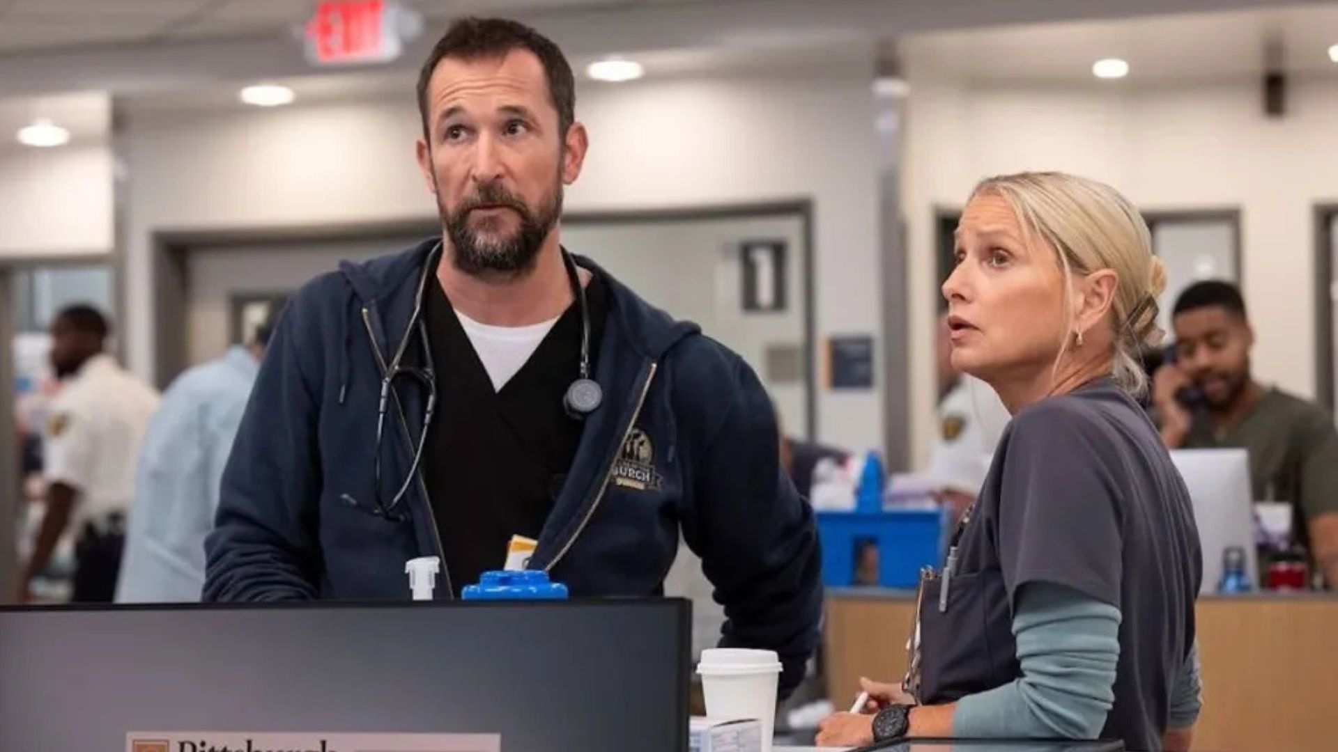 Robbie and Dana look at the ER screen above reception