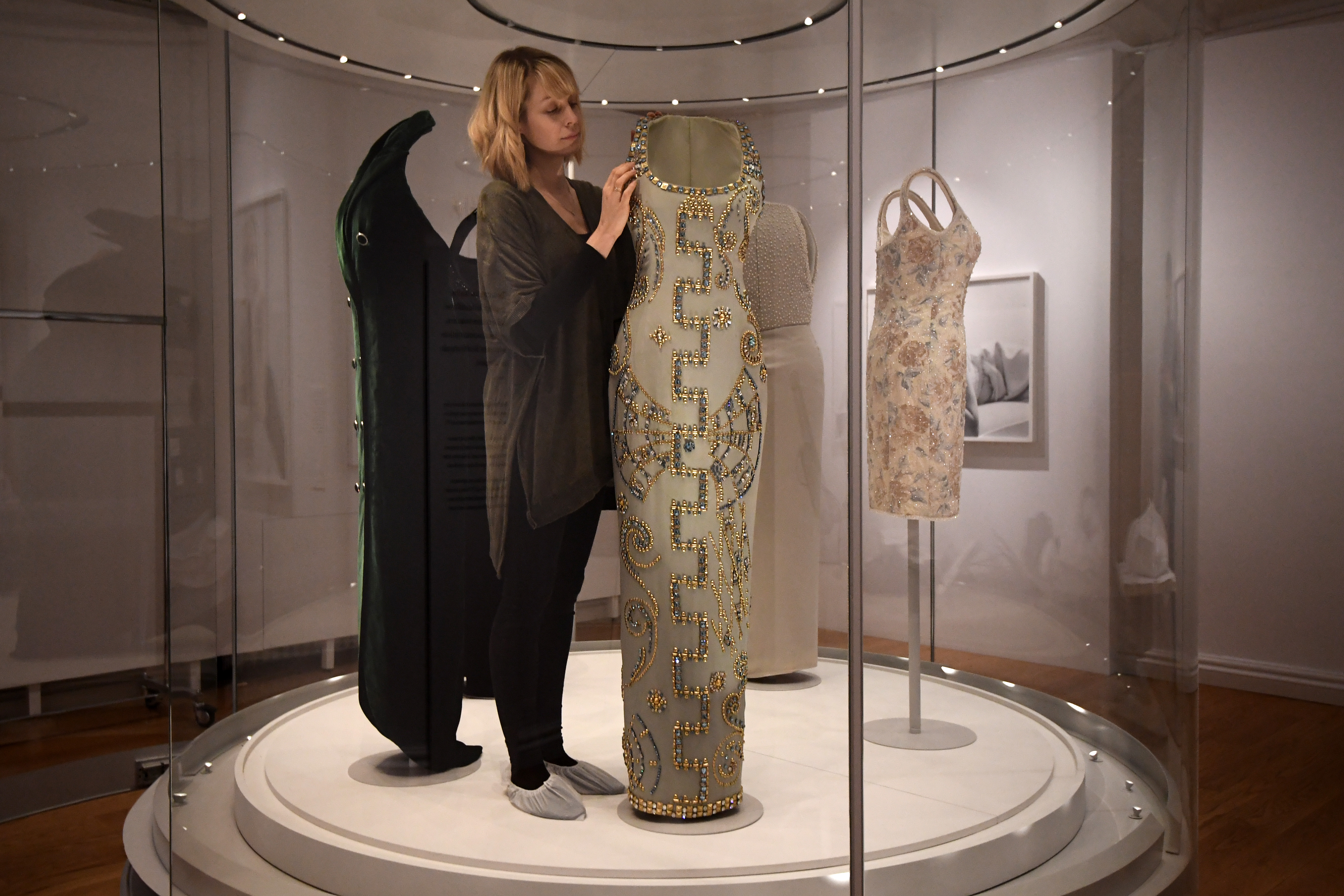 A member of staff poses with a 1991 Versace ice-blue silk gown with beading worn for a Harper&amp;amp;apos;s Bazaar photo-shoot (Photo by Carl Court/Getty Images)