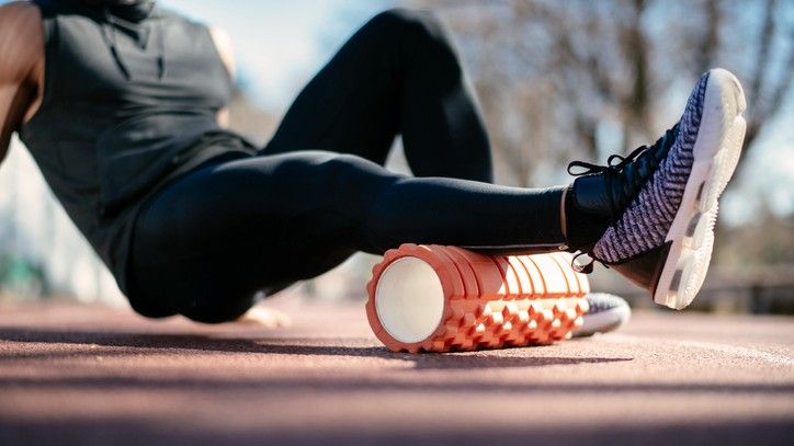 foam roller exercises: person using a foam roller outdoors to ease stiffness in his calves