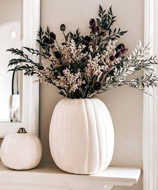 white diy pumpkin vase with fresh foliage on a mantel